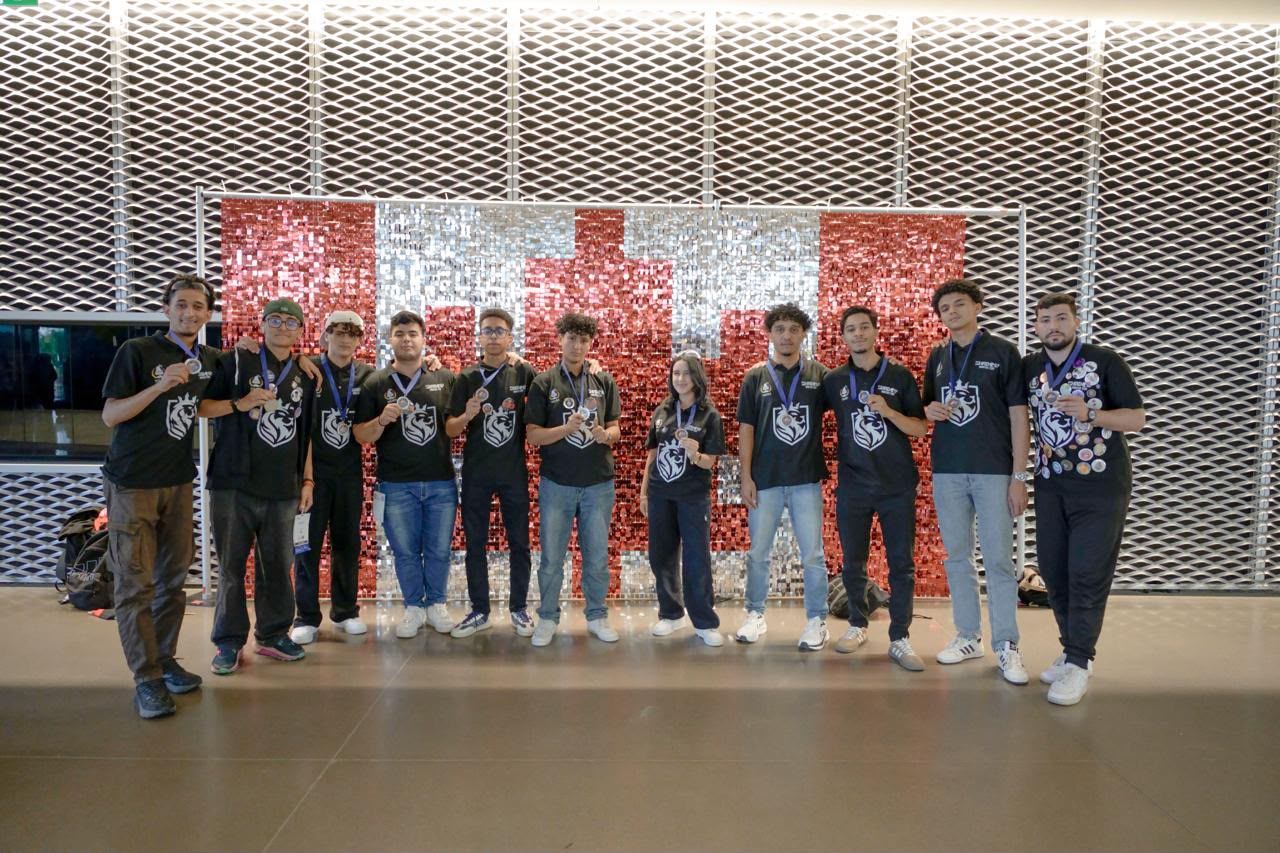 Team members in black team shirts line up for a group photo in front of a sequinned backdrop.